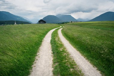 Avusturya Alpleri ve fırtınalı havası olan kiliseleri olan çim çayırlarından köylere giden yol, Mieminger Platosu, Tyrol, Avusturya