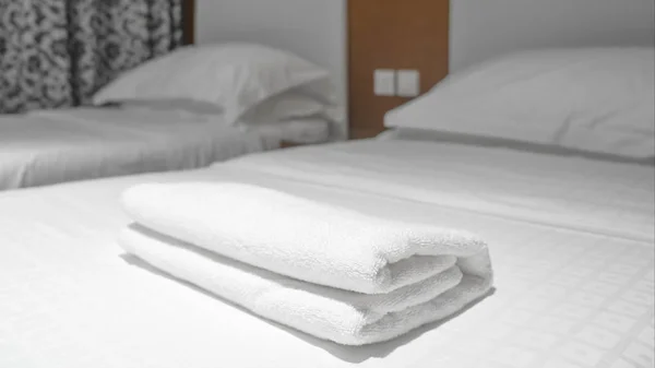 white towel on white bed in bed room