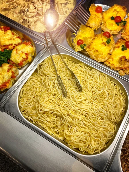 Spaghetti and Penne Pasta steaming hot in serving dishes on a buffet