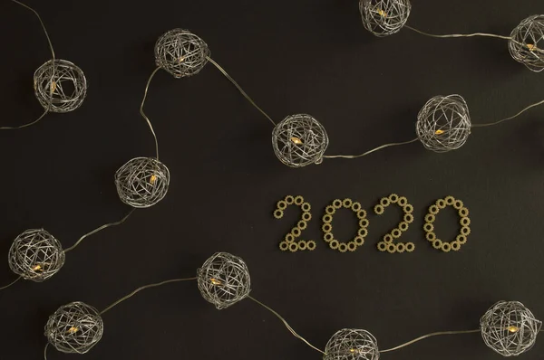 2020 yılının kutlaması. Metalik tema. 2020 numaralı makarnanın etrafını saran güzel küresel ışıklar. Moda konsepti.
