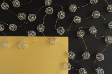 Noel kartı. Metalik küresel ışıklarla çevrili altın ve koyu siyah kara zemin üzerindeki metin için boş bir yer