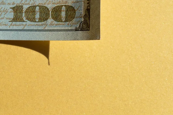 Pièce de billet de 100 dollars au coin supérieur gauche sur le fond jaune doré. Photo conceptuelle, design minimaliste — Photo