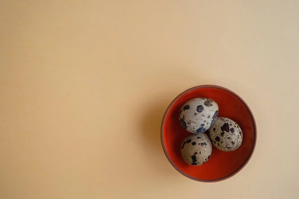 Açık sarı zemin üzerinde üç bıldırcın yumurtası olan küçük bir kase. Paskalya Tatili 2020 için son moda kavramsal minimalist fotoğraf