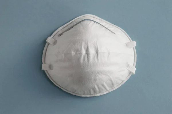 Kirlilik ve virüse karşı korunmak için açık mavi arka planda beyaz tıbbi maske, koronavirüs. Sağlık hizmeti kavramı