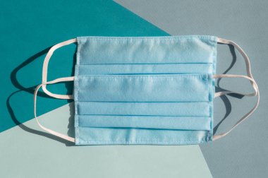 Mavi ve turkuaz arka planların karışımında iki açık mavi tek kullanımlık yüz maskesi virüse karşı covid-2019. Sağlık bakımı konsepti, karantina, koronavirüsü durdurun..