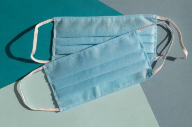 Mavi ve turkuaz arka planların karışımında iki açık mavi tek kullanımlık yüz maskesi virüse karşı covid-2019. Sağlık bakımı konsepti, karantina, koronavirüsü durdurun..