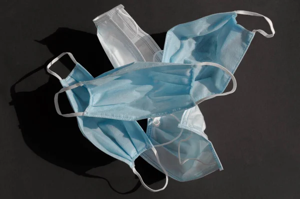 Koyu siyah arka planda kullanılan beş açık mavi tek kullanımlık tıbbi yüz maskesi virüse karşı covid-2019. Sağlık bakımı konsepti, karantina, koronavirüsü durdurun..