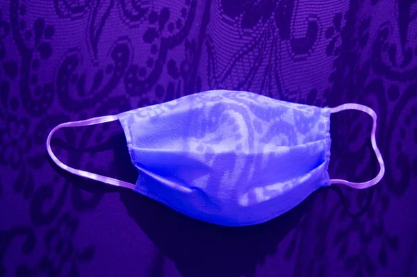 Tıbbi maske, 2019 yılının güneş ışığı altında gölgeli virüse karşı. Siyah arka planda koyu mor neon bir ton. Heath care konsepti, koronavirüsü durdurun..