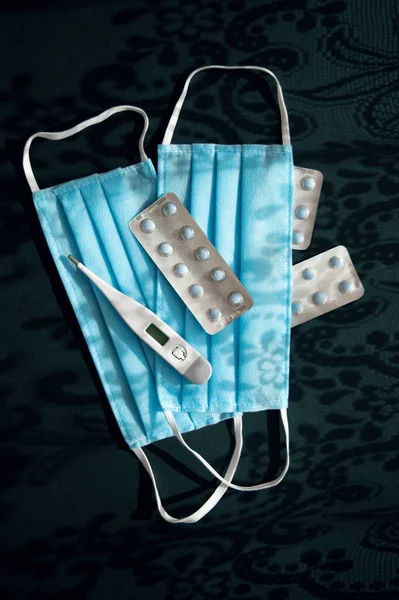 Karanlık zümrüt zümrüt zümrüt zümrüt zemininde iki mavi tıbbi maskenin dikey fotoğrafı virüs covid-2019 'a karşı. Heath care konsepti, koronavirüsü durdurun..