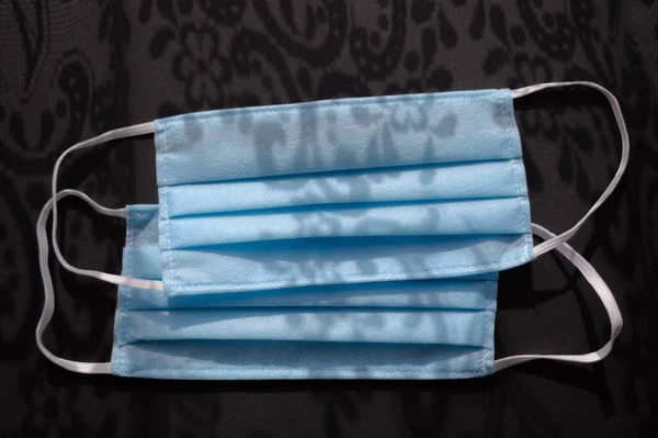 Koyu siyah arkaplandaki açık mavi tek kullanımlık yüz maskeleri virüse karşı 2019. Sağlık bakımı konsepti, karantina, koronavirüsü durdurun..