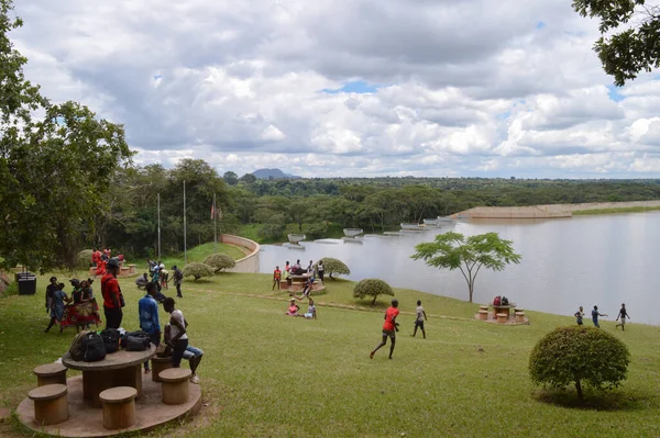 LILONGWE, MALAWI, AFRICA - 1 NİSAN 2018: Afrikalı gençler çimlerin üzerinde zıplayarak ve dans ederek parti veriyorlar. Kırmızı tişörtlü bir çocuk Kamuzu Barajı II 'ye koşuyor..