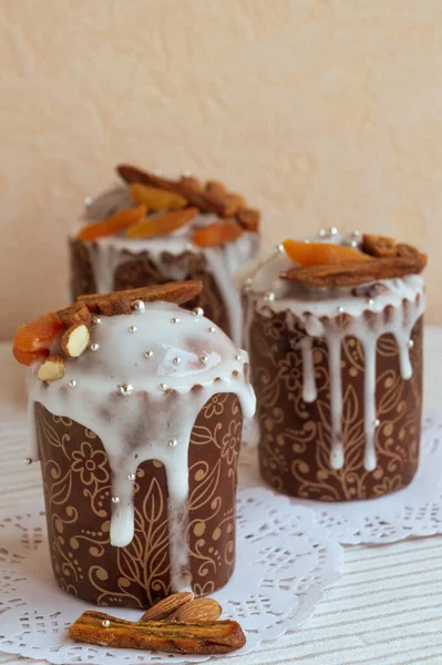 Beyaz peçetede ev yapımı Paskalya kekleri ve arka planda kurutulmuş muzlar, turuncu kayısılar, bademler ve küçük zarif şeker gümüşü inci boncuklar ile dekore edilmiş olanlar. Dikey fotoğraf, şık bir fikir.