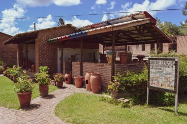 DEDZA, MALAWI, AFRICA - 25 Mart 2018: Dedza Çömlekçiliğinin girişi yakınında. Açık kahverengi tuğlalı binalar. Saksılarda yeşil bitkiler, çimenler. Seramik masasında duyuru.