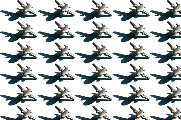 Beyaz arka planda gölgeleri olan küçük gümüş renkli uçakların 30 metal figürü. Kavramsal geometrik sanat modayı. Havacılık endüstrisi arka planında sıra sıra uçak var.