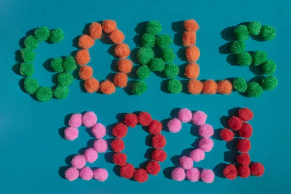 2021 yılının hedefleri, koyu turkuaz arka planda 2021 yılının sembolü olarak, yeşil, turuncu, pembe ve kırmızı renklerden oluşan çok renkli ponponlardan oluşan şenlikli bir başlık. Gelecekteki planlar için trend fikrini kabul et