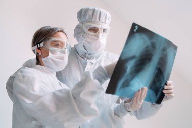 Beyaz arka planda duran doktorlar klinikteki Covid-19 hastasının zatürresi için röntgen çekiyorlar. Coronavirus konsepti