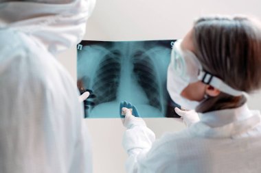 Beyaz arka planda duran doktorlar klinikteki Covid-19 hastasının zatürresi için röntgen çekiyorlar. Coronavirus konsepti
