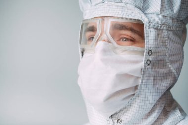 Tıbbi maske, koruyucu gözlük ve kimyasal elbise takmış Avrupalı bir erkek doktorun portresi.