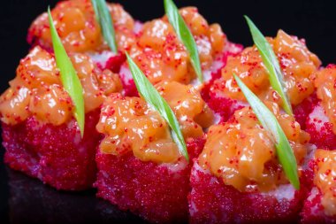 Somonlu suşi, siyah arka planda baharatlı sos.