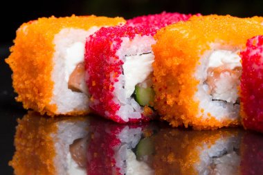 Suşi siyah arka planda California 'yı yuvarlıyor.