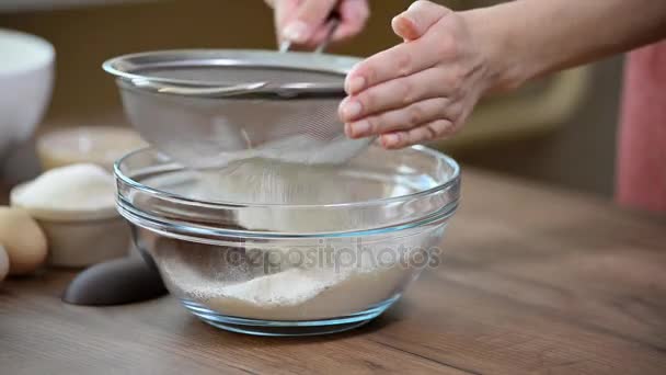 Sifting flour into bowl on table on wooden background — Stock Video