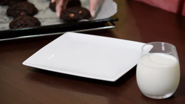 Женская рука кладет шоколадное печенье в миску — стоковое видео