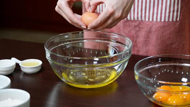 Żeńskie dłonie rozbijające jajko i oddzielające żółtko od białego. — Wideo stockowe