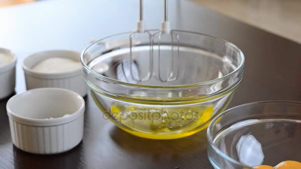 Woman whisking eggs whites with mixer into glass bowl — Stock Video