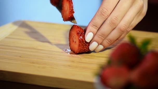 Крупним планом жіночі руки розрізають і нарізають полуницю на дошці — стокове відео