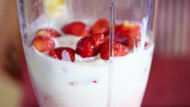 Çilek smoothie yapmak için bir blender kullanan kadın