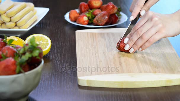 Крупним планом жіночі руки розрізають і нарізають полуницю на дошці — стокове відео