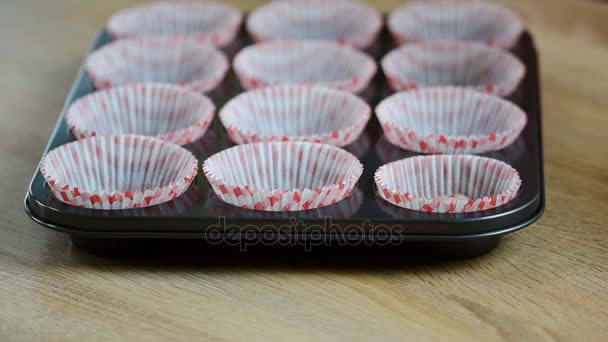 Mettere l'impasto in bicchieri di carta. Versare l'impasto della torta a mano nel vassoio dei muffin — Video Stock