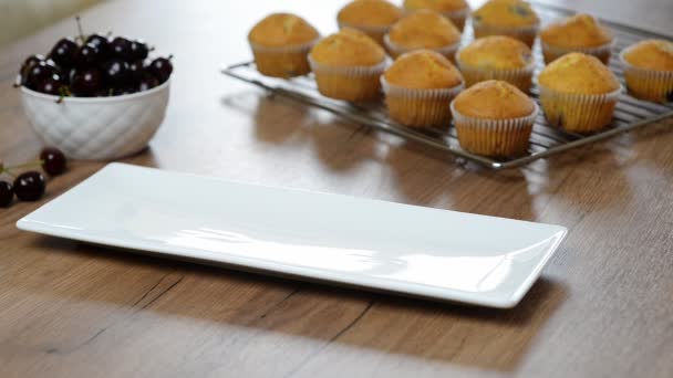 Ragazza mette un piatto bianco di muffin — Video Stock