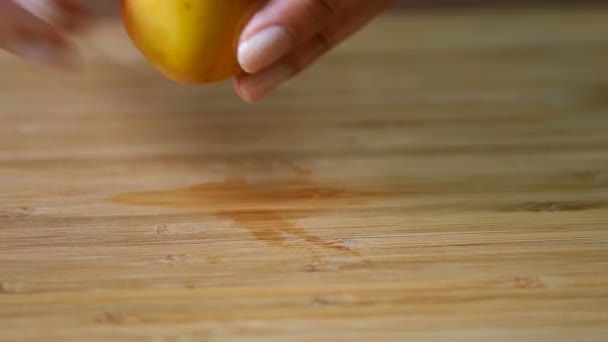 Vrouwelijke handen snijden abrikoos op houten bord — Stockvideo