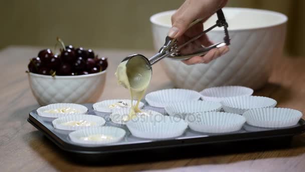 Put the dough into paper cups. Hand pouring cake dough into muffin tray — Stock Video