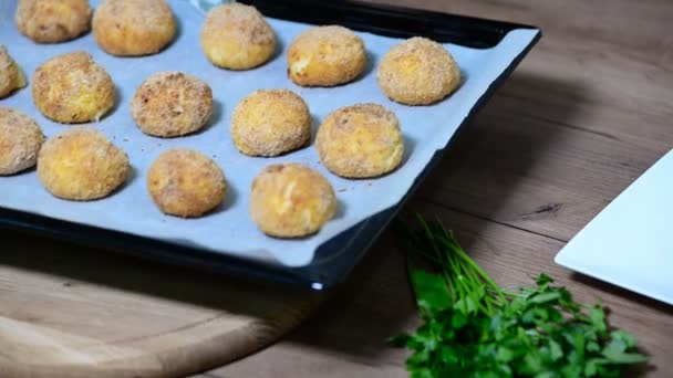 Arancini gebakken met kaas schnitzels schotel bedekt met broodkruimels, Panko kruimels op een snijplank naast lade bakken. — Stockvideo