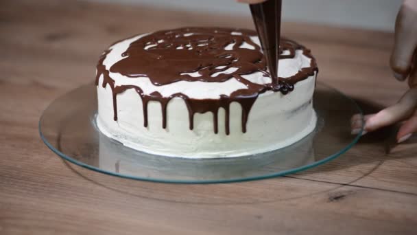 Vrouwelijke chef-kok koken voorbereiding van een zoete cake in de keuken, de chocolade crème daarop gieten — Stockvideo