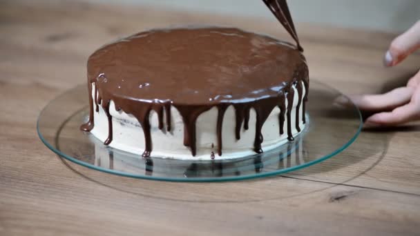 Жіночий шеф-кухар готує солодкий торт на кухні, наливаючи на нього шоколадний крем — стокове відео