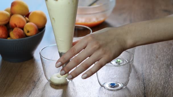 Vrouwelijke hand knijpen de crème van de spuitzak in een glas — Stockvideo