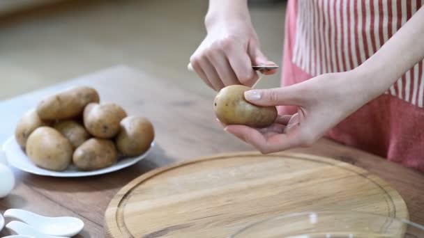 Skalar en potatis. Kvinnans händer peeling potatis i köket — Stockvideo