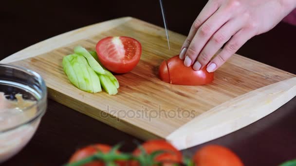 Mujer joven cortando tomates en la cocina para ensalada fresca — Vídeo de stock