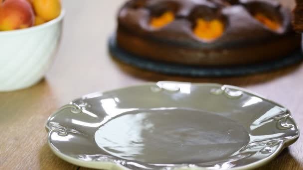 Положить в тарелку кусочек шоколадного торта с абрикосами — стоковое видео