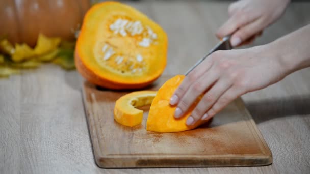 切削生カボチャ スライス。女性はオレンジのカボチャの部分をカットします。生かぼちゃカット — ストック動画