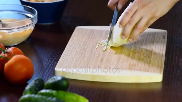 Female hands cut a green salad with knife on wooden board. Close up of knife cuts cabbage. — Stock Video