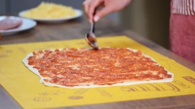 Domates sosu pizza üzerine koyarak