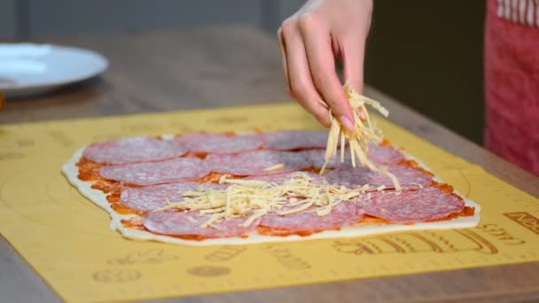 En kvinnlig hand strössel pizza med riven ost närbild. — Stockvideo