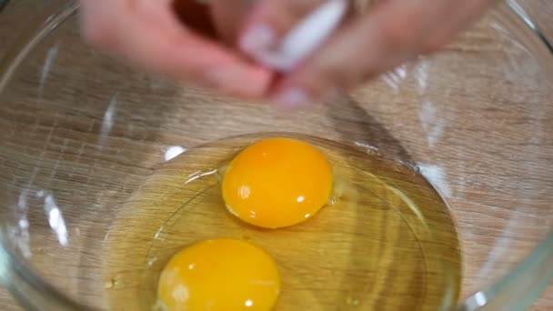 Девушка разбивает яйцо в миске — стоковое видео