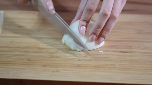 Manos del chef con cuchillo cortando la cebolla en la tabla de madera. — Vídeo de stock