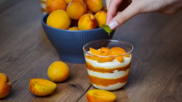 Woman decorates mint leaves apricot mousse — Stock Video