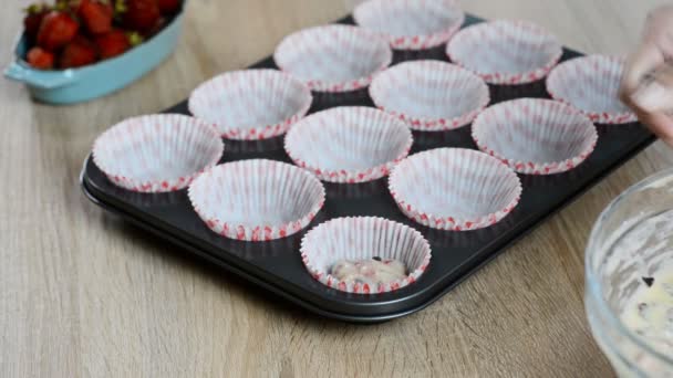 Put the dough into paper cups. Hand pouring cake dough into muffin tray — Stock Video